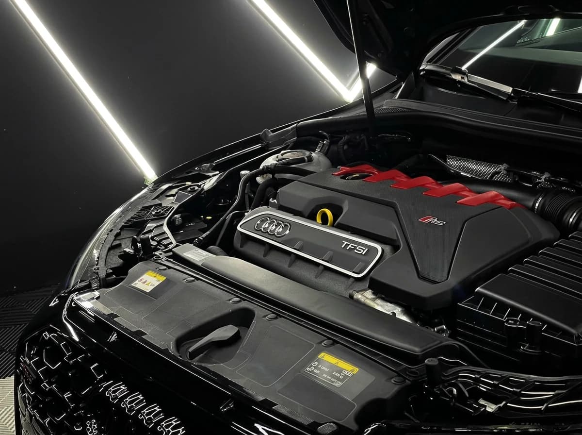 Compartiment moteur ouvert d'une Audi RS3, cinq cylindres 2.5 TFSI et cache moteur à inserts rouges