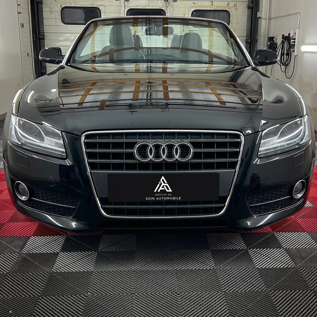 Audi A5 Cabriolet noire vue de face dans l'atelier, calandre et quatre anneaux au premier plan