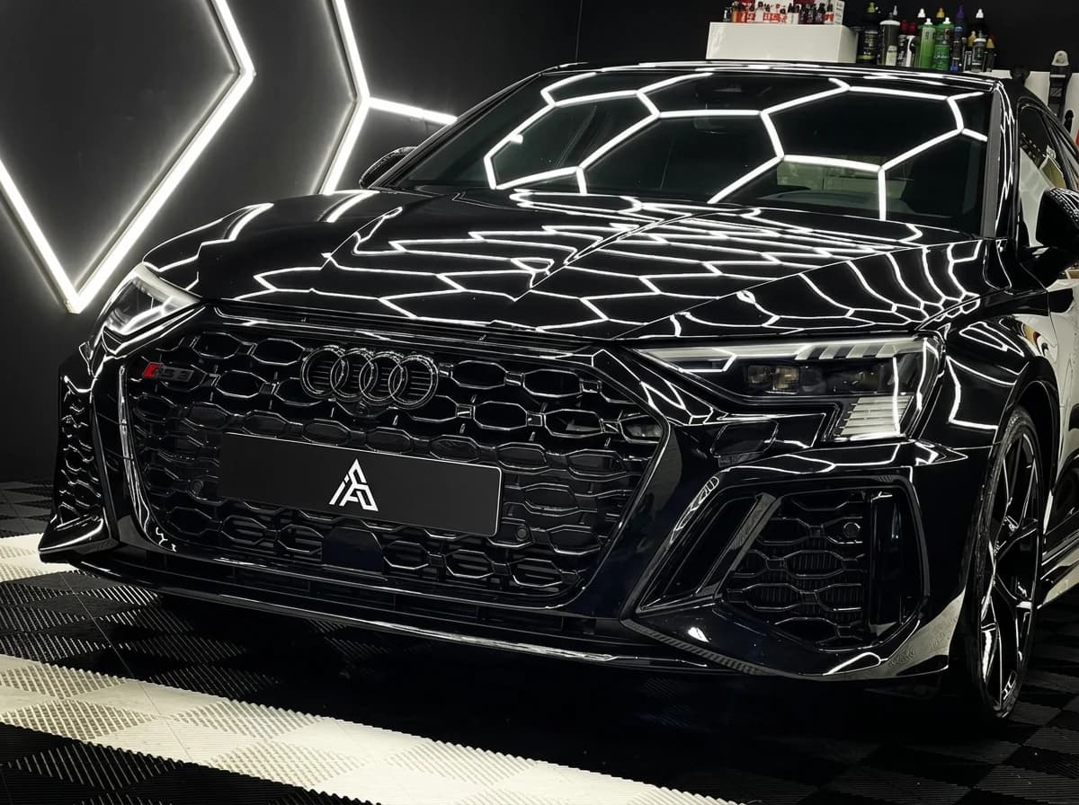 Audi RS3 noire vue de face dans le studio, calandre nid d'abeille éclairée par les LEDs