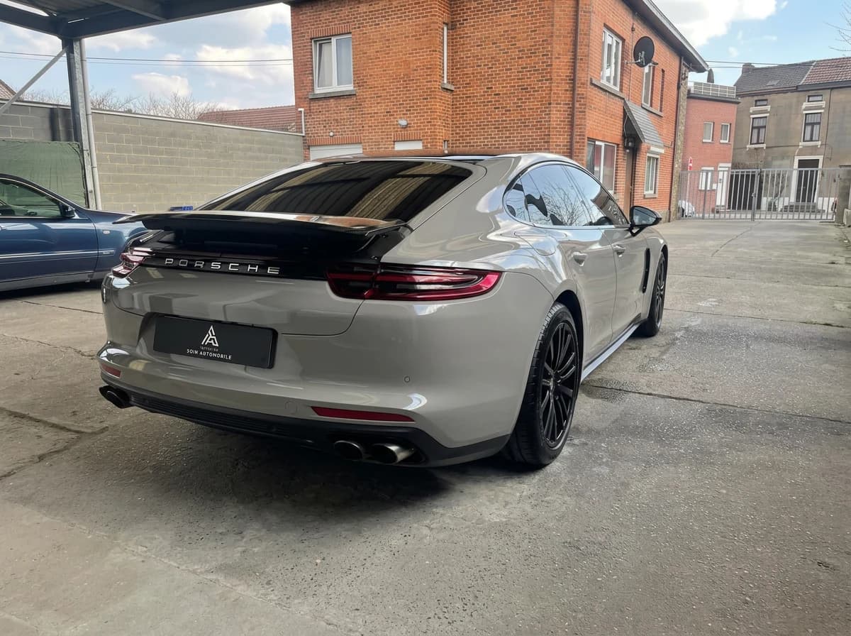 Porsche Panamera Sport Turismo grise de trois quarts arrière dans une cour en béton