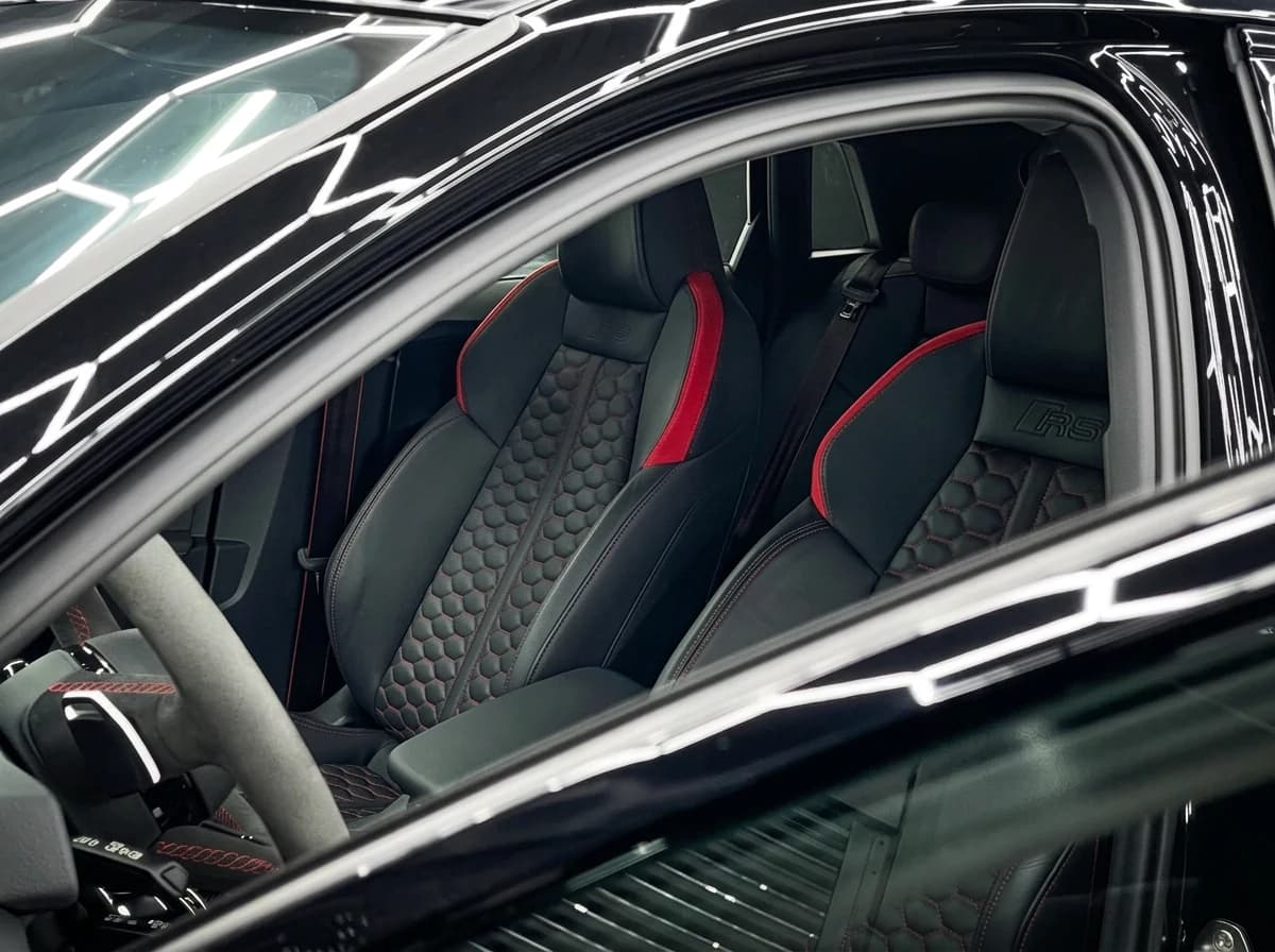 Sièges baquets RS matelassés nid d'abeille avec surpiqûres rouges, vus par la portière ouverte d'une Audi RS3