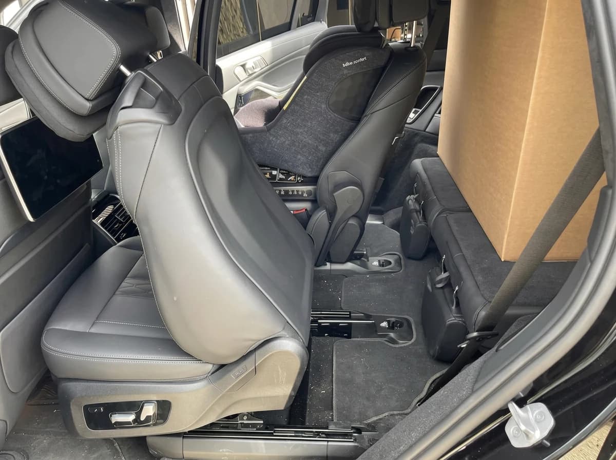 Accès à la deuxième rangée d'une BMW X7, siège avant rabattu, cuir noir et ceinture apparente