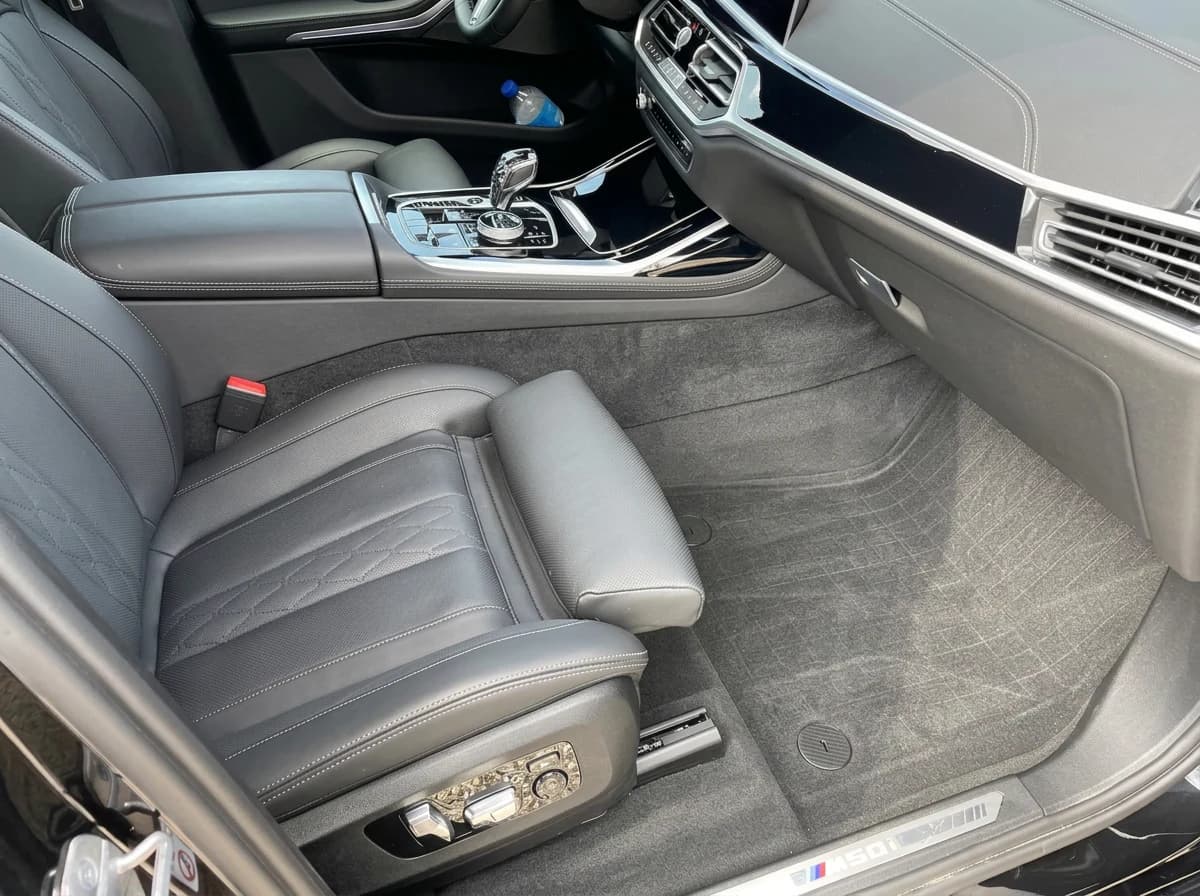 Place passager avant d'une BMW X7 après nettoyage : moquette propre, traces d'aspirateur encore visibles