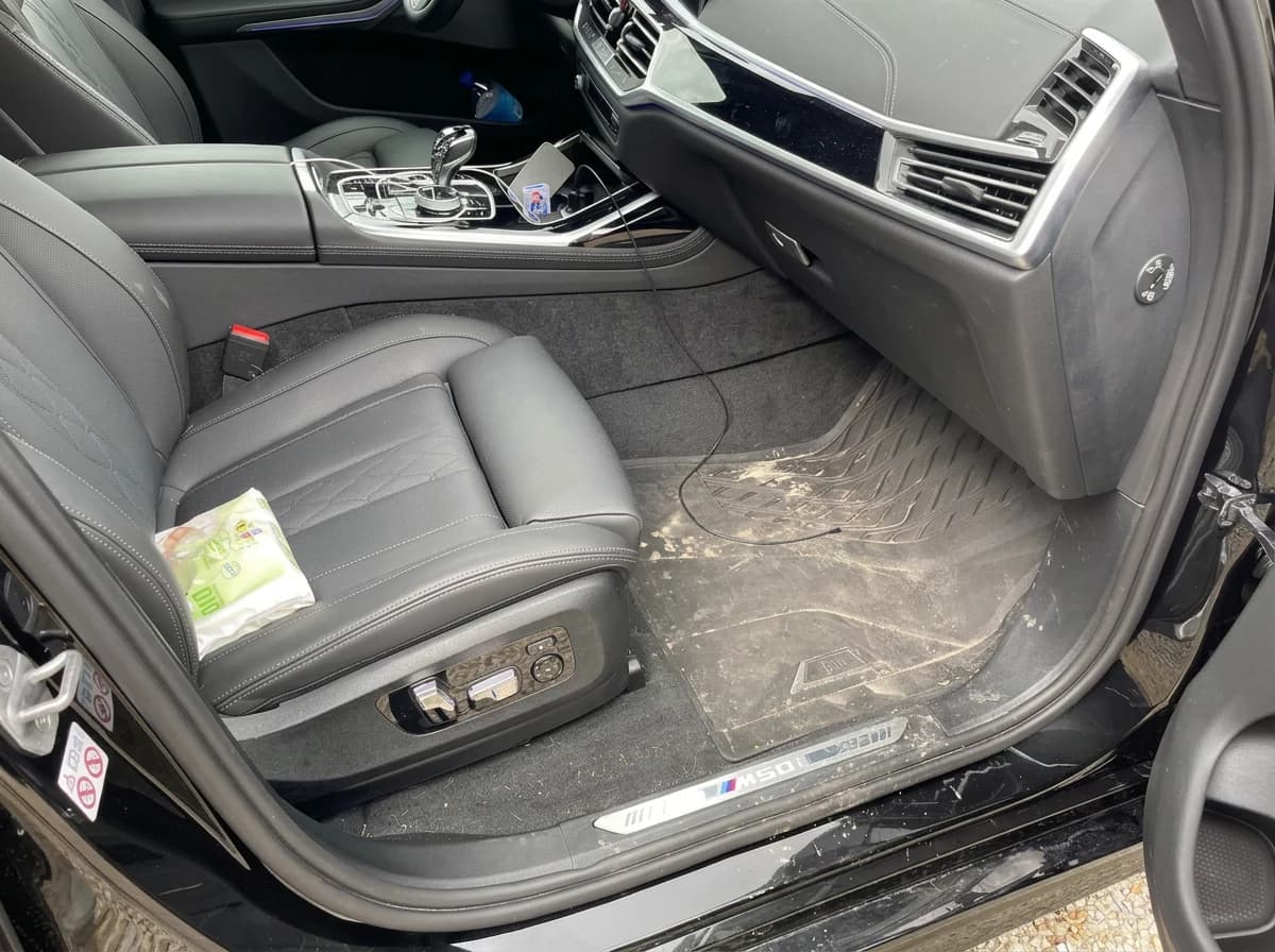 Place passager avant d'une BMW X7 avant nettoyage : moquette et tapis très encrassés