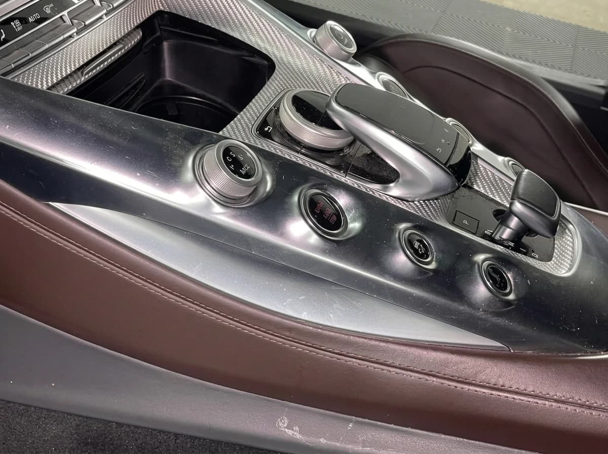 Console centrale en aluminium brossé d'une Mercedes-AMG GT, ses huit boutons ronds disposés en V et le sélecteur