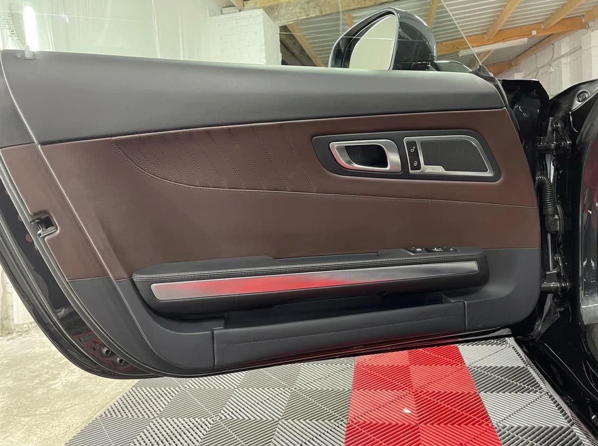 Portière conducteur ouverte d'une Mercedes-AMG GT vue de l'extérieur : panneau en cuir brun et bandeau lumineux rouge
