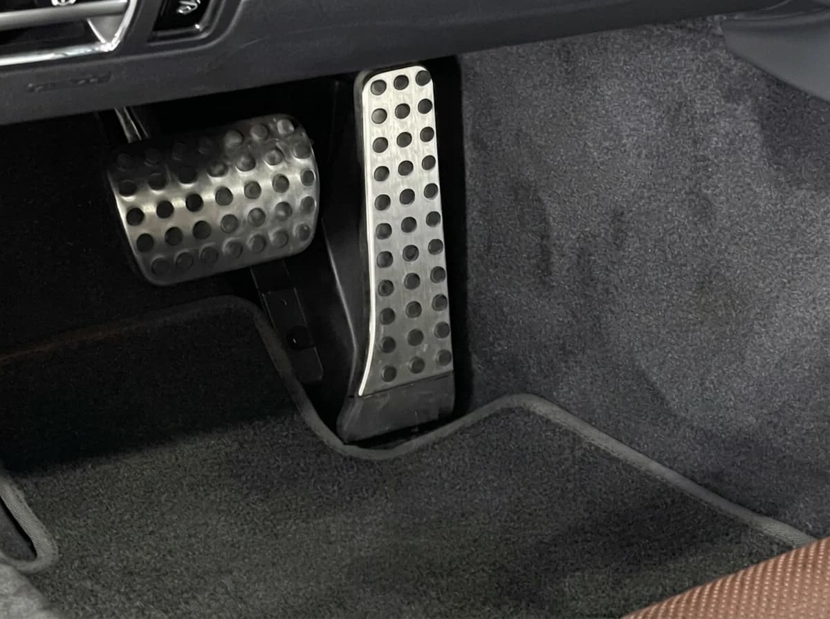 Macro sur le pédalier en inox perforé d'une Mercedes-AMG GT et la moquette du tablier