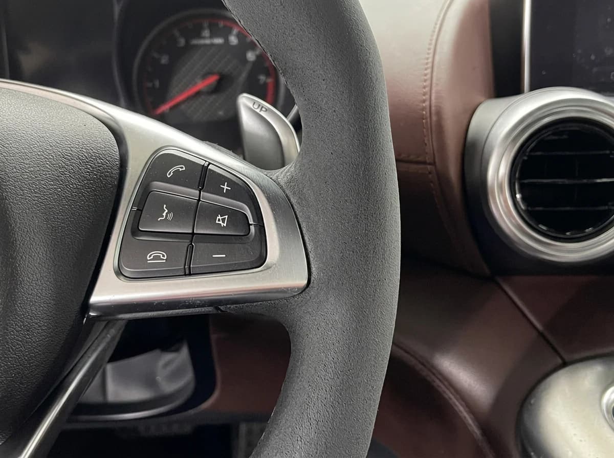 Volant et compteur d'une Mercedes-AMG GT en légère contre-plongée, aérateur rond en forme de turbine