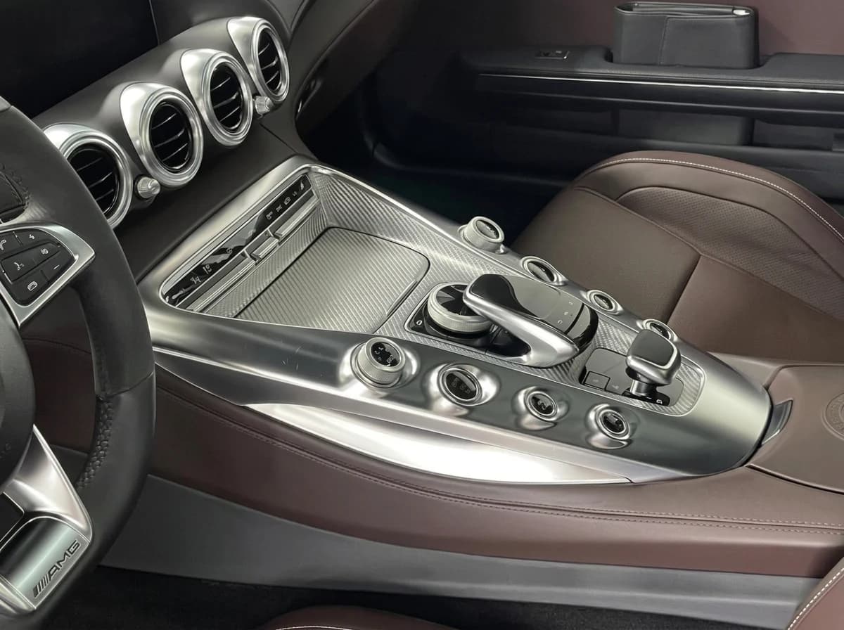 Vue traversante de l'habitacle d'une Mercedes-AMG GT depuis le poste de conduite, rangée d'aérateurs ronds et console centrale