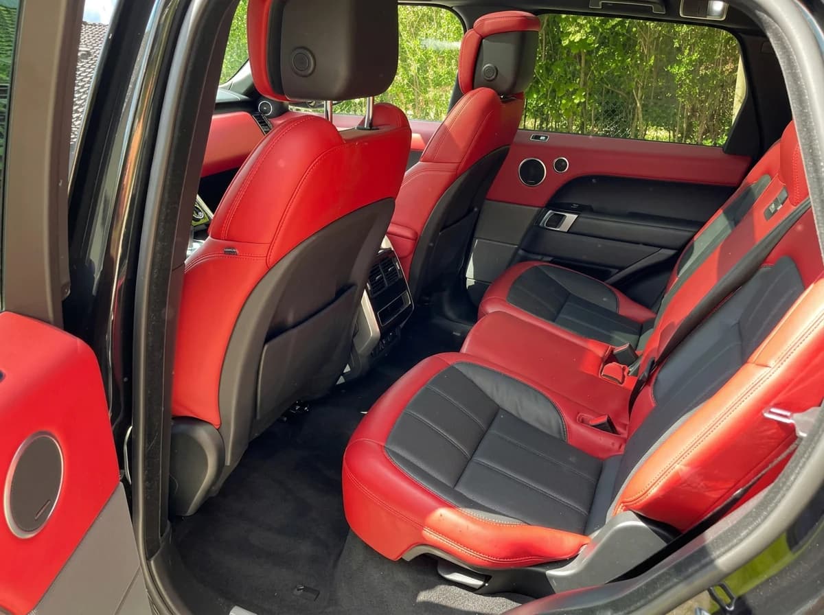 Banquette arrière en cuir rouge et noir d'un Range Rover Sport, vue par la portière ouverte