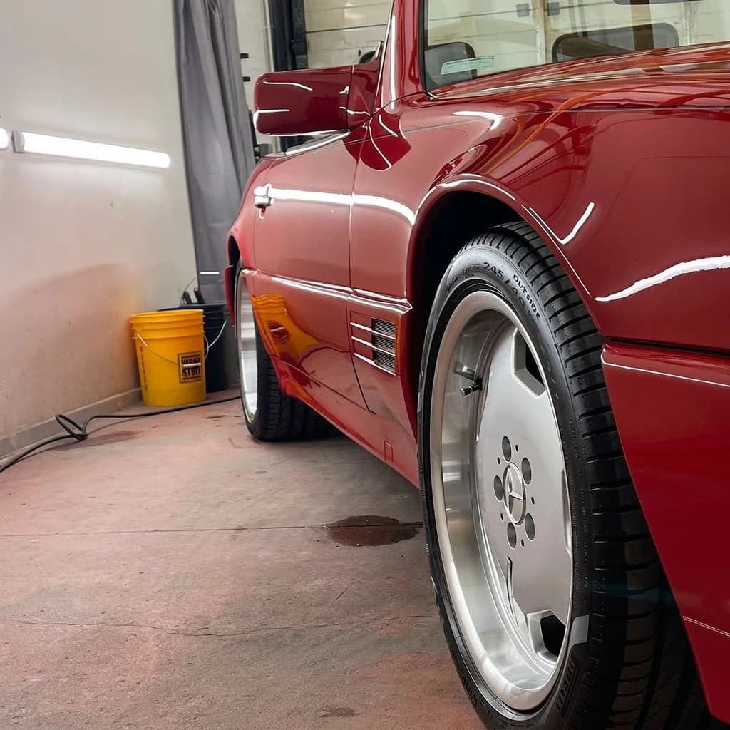 Plan serré sur l'aile avant rouge d'une Mercedes 500 SL, l'ouïe latérale et la jante Monoblock polie