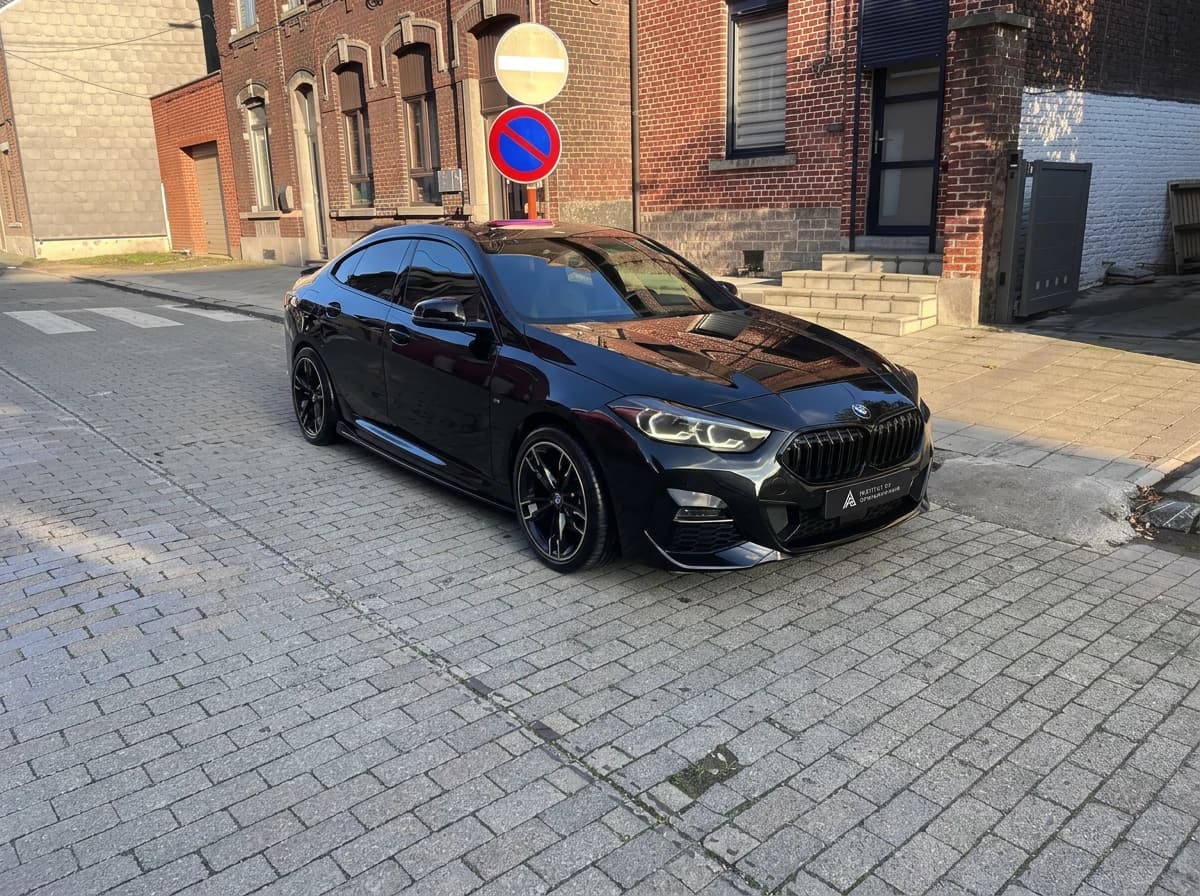 BMW Série 2 Gran Coupé noire de trois quarts avant dans la lumière rasante de fin de journée