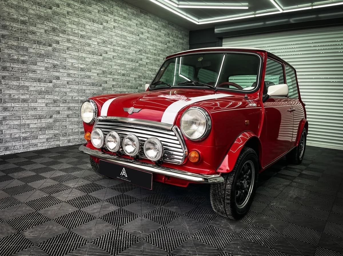 Mini classique rouge à bandes blanches vue de face dans l'atelier, quatre phares longue portée sur la calandre