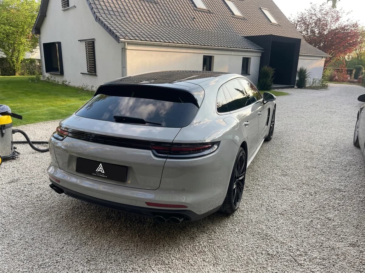 Porsche Panamera Sport Turismo gris clair de trois quarts arrière devant une maison, pelouse au premier plan