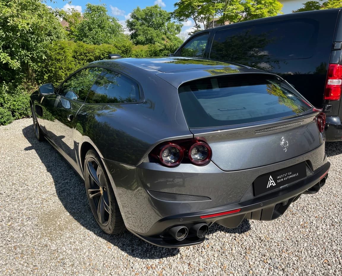 Ferrari GTC4Lusso gris foncé de trois quarts arrière dans une allée en graviers bordée d'arbres