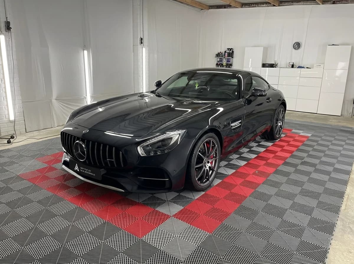 Mercedes-AMG GT noire de trois quarts avant dans l'atelier ISA, posée sur le sol à damier gris et rouge