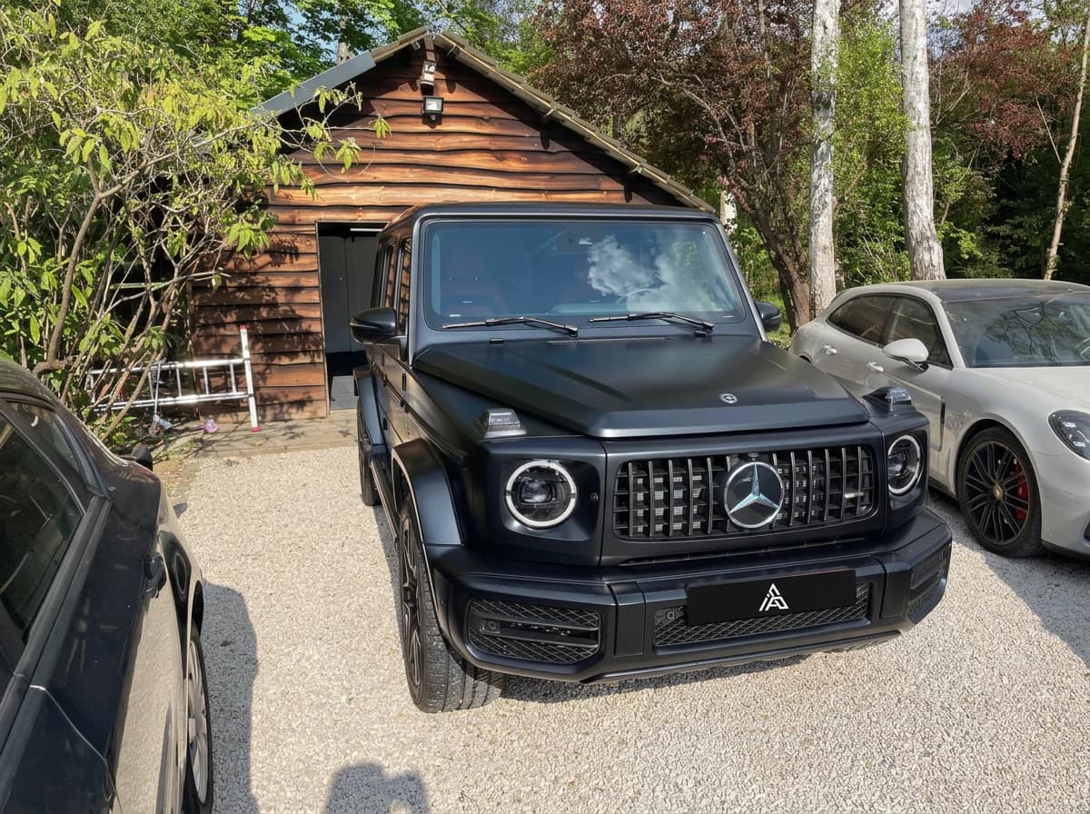 Mercedes-AMG G63 noir mat de trois quarts avant devant un hangar en bois