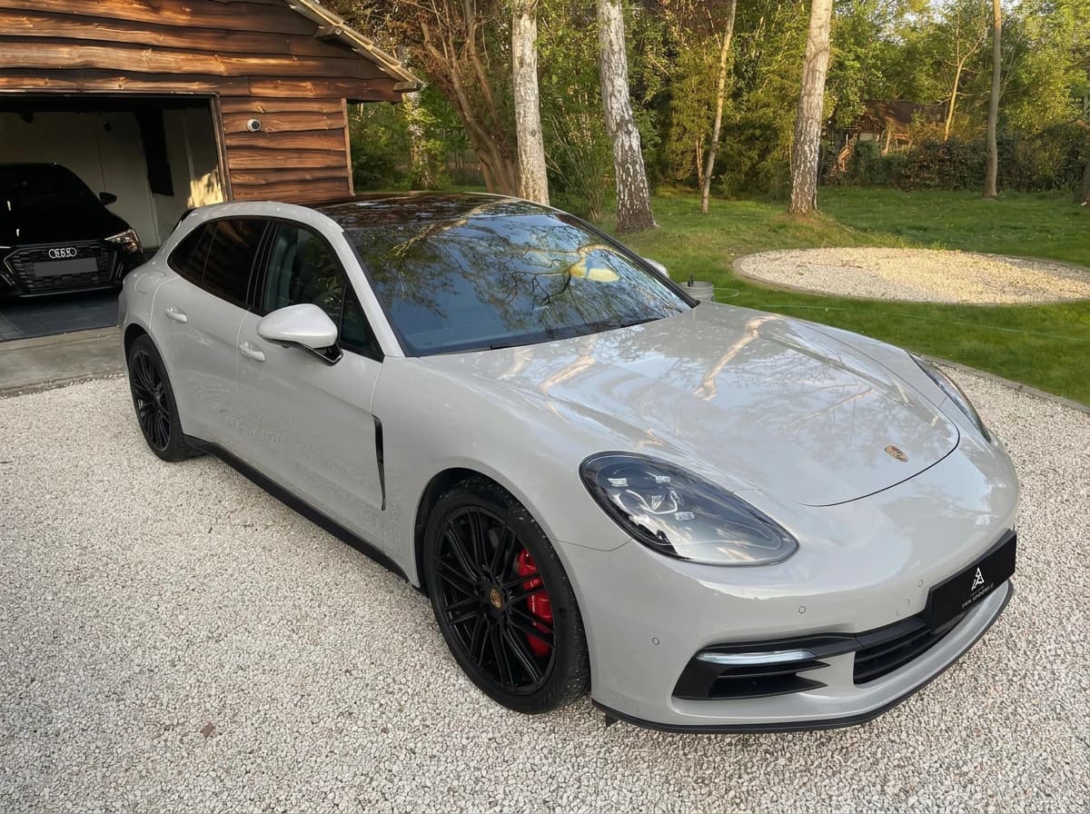 Porsche Panamera Sport Turismo gris clair de trois quarts avant devant une grange en bois